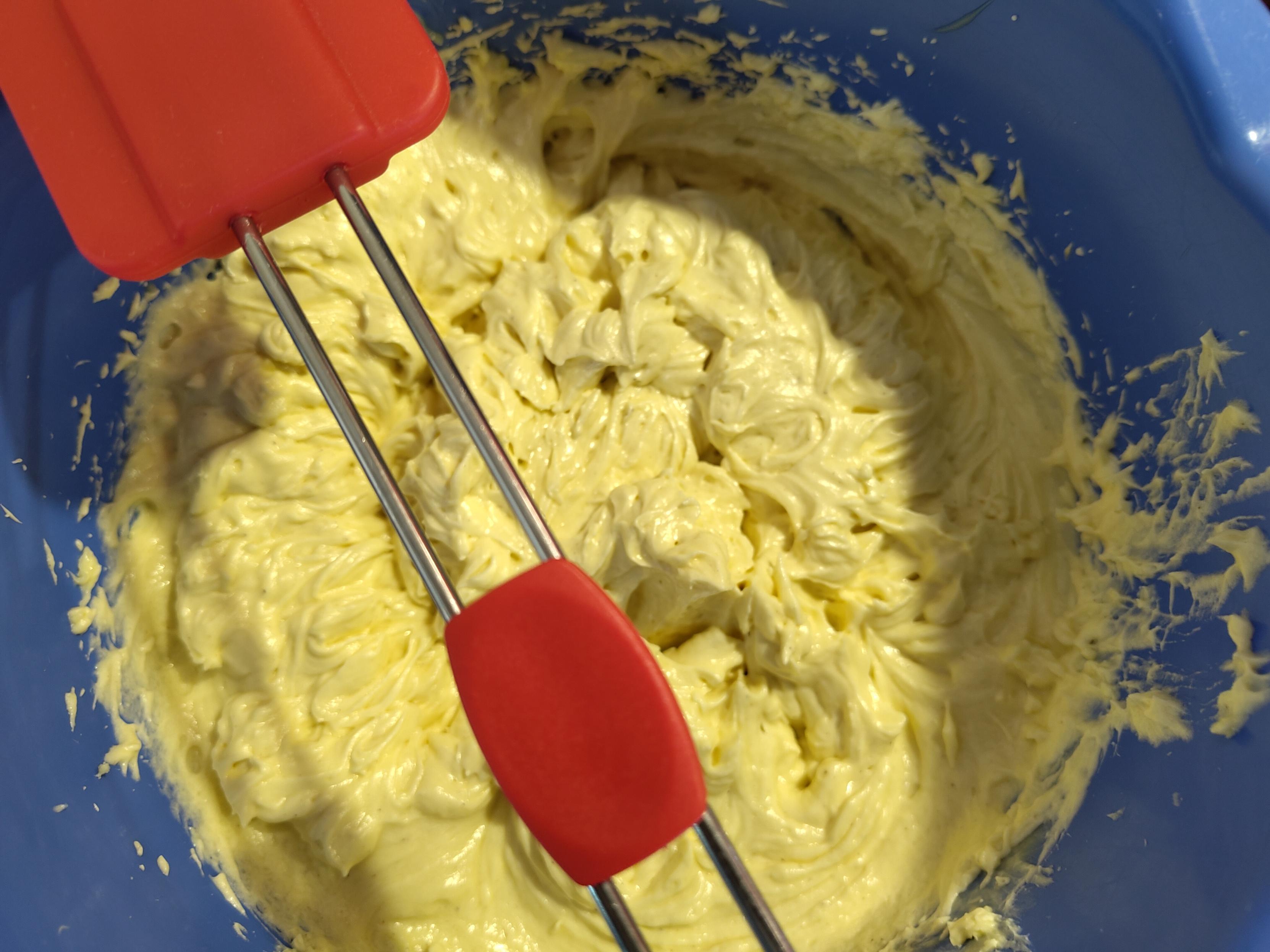 Vanillepudding/Margarine Creme in einer blauen Rührschüssel. Ein roter Teigschaber liegt quer über der Schüssel.