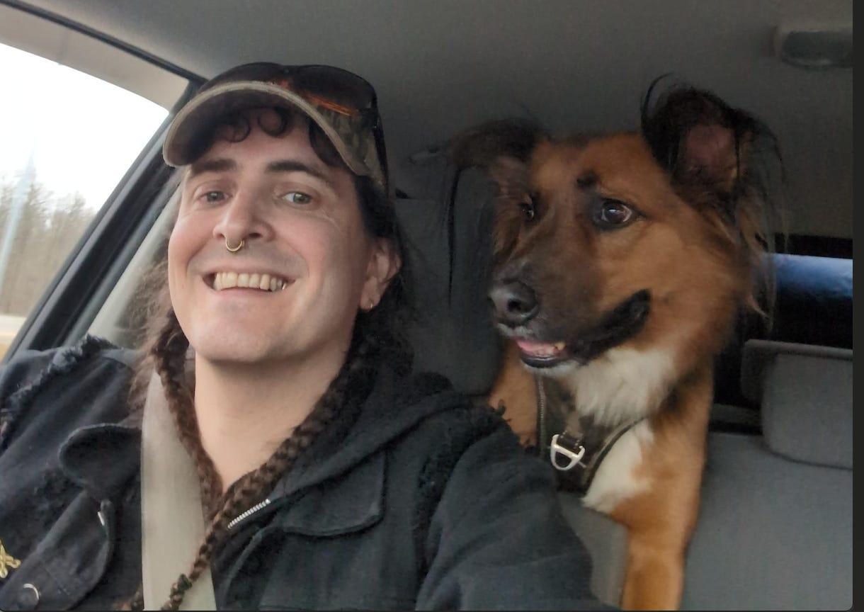 Das Foto zeigt Margaret Killjoy im Auto und ihren Hund Rintrah, der ihr über die Schulter schaut