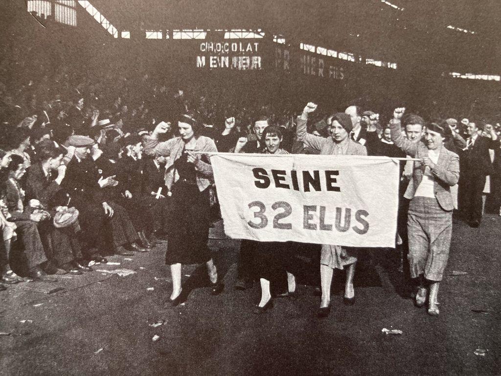 Das historische Foto zeigt die Szenerie einer Demonstration mit einem getragenen Transparent mit dem Text "Seine 32 elus"